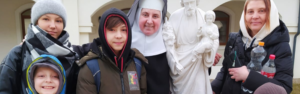 Hermana benedictina con una familia y una estatua de San José y el Niño Jesús